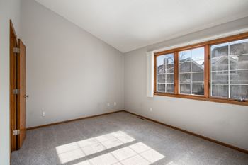 an empty bedroom with large windows and carpeting at Seasons Villas, Minnesota, 55125